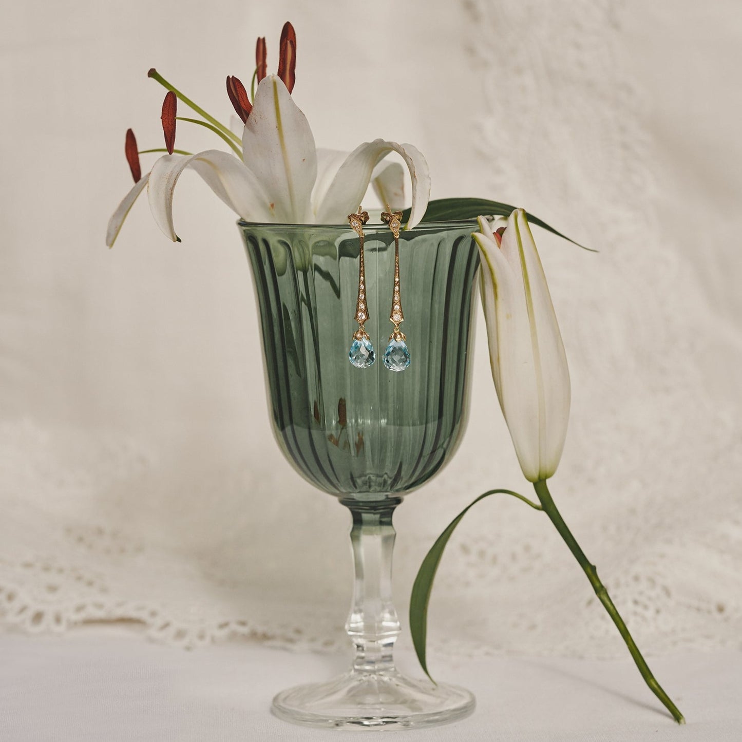 Bodegón de los pendientes Béatrice que cuelgan de una copa con flores.