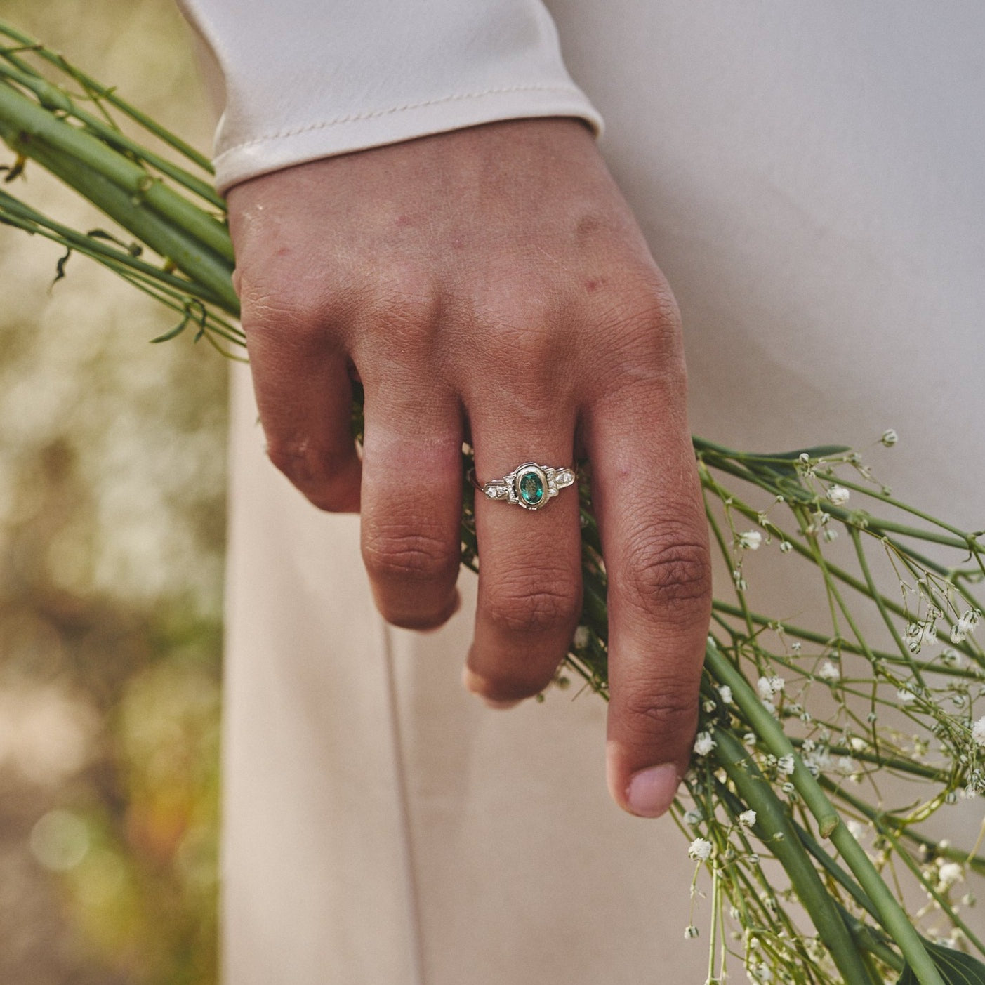 Mano sujetando unas flores y mostrando el anillo Louise.