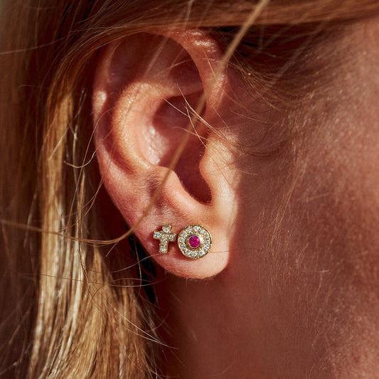 Detalle de la oreja de la modelo con el uno de los Pendientes Ciel, con forma de cruz. Elaborado en oro de 9k con seis diamantes lab-grown. A su lado, la modelo luce otro de los pendientes de la marca, uno de los Pendientes Marie, también fabricado con oro de 9k y diamantes.