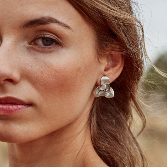 Pendiente Floralis tamaño grande y acabado mate. Se aprecian los detalles de los pétalos que dan volumen a la pieza hecha a mano.