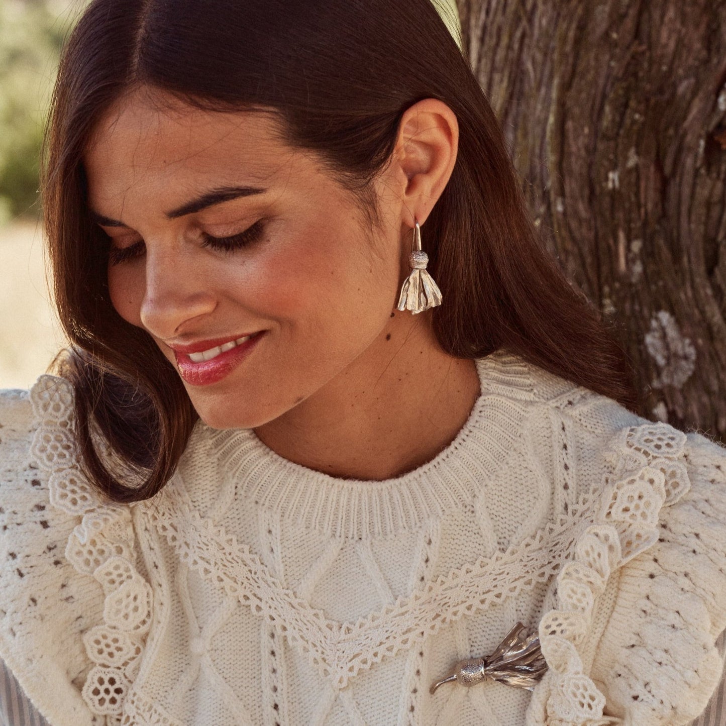 Mujer sonriente con el Broche Autumn Flower y los pendientes a juego. Son piezas hechas con plata de ley que tienen forma de una flor de otoño.