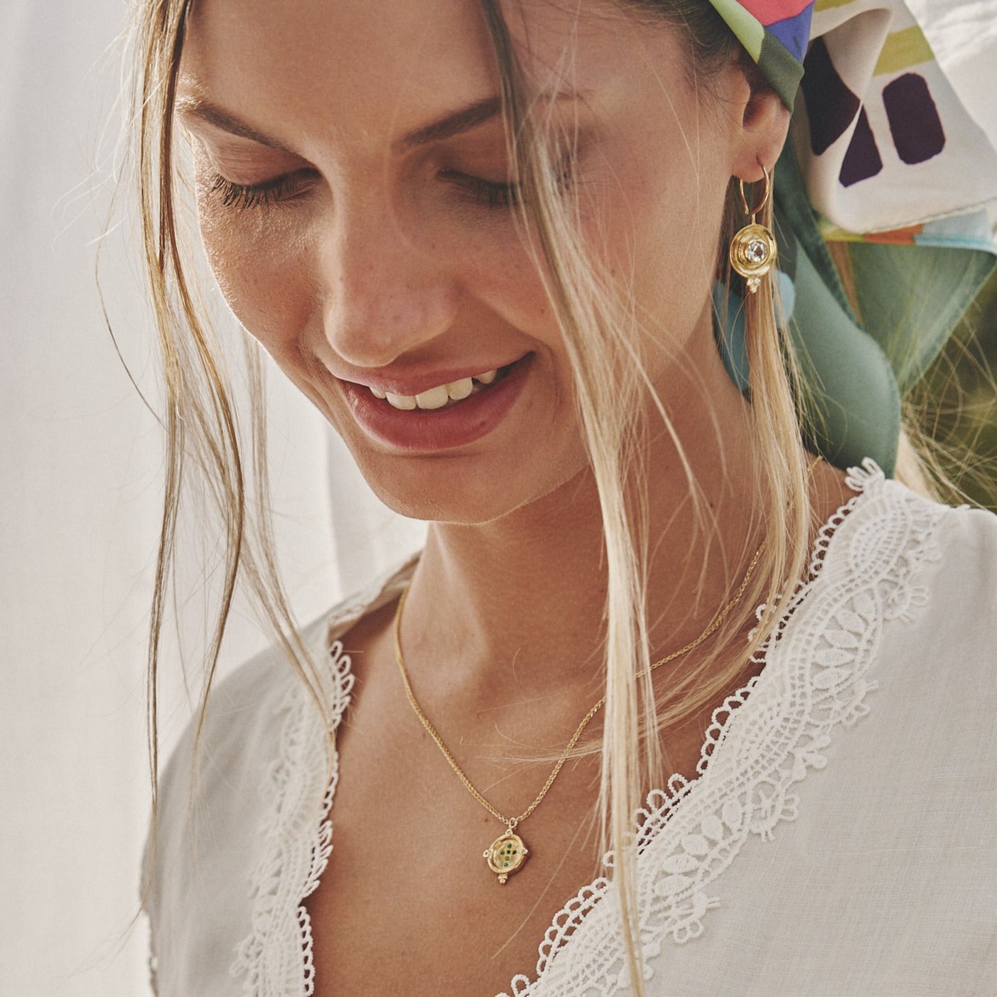 Mujer sonriendo con los pendientes Josephine de oro, con aguamarinas y diamantes.