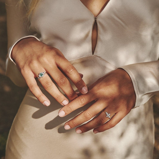 Manos de una mujer mostrando el anillo de compromiso Louise y el anillo Fiorelli.