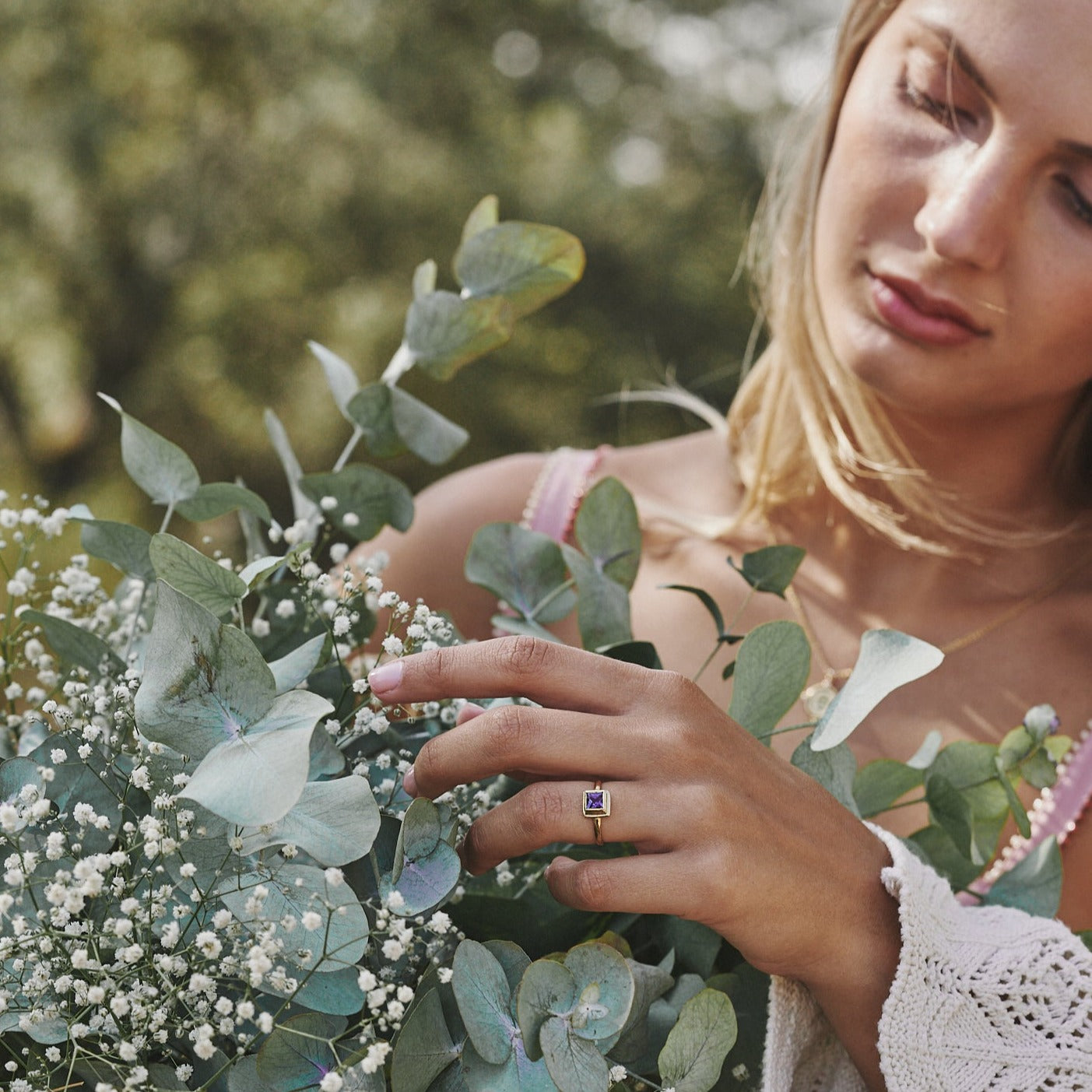 Mujer sujetando un ramo de flores y mostrando el anillo Ludovica, fabricado artesanalmente en España.