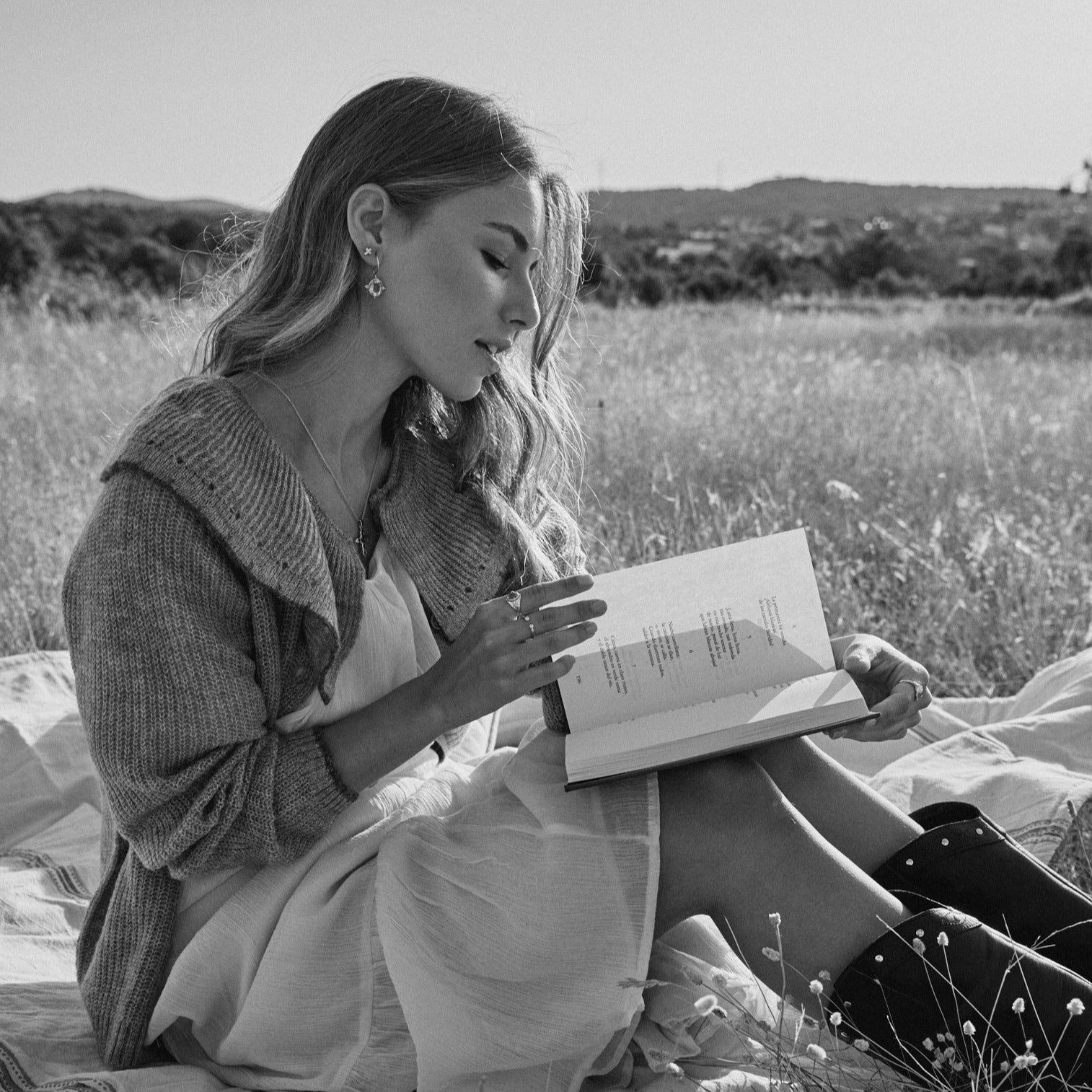 Modelo leyendo un libro en el campo con los Pendientes Opehlia.
