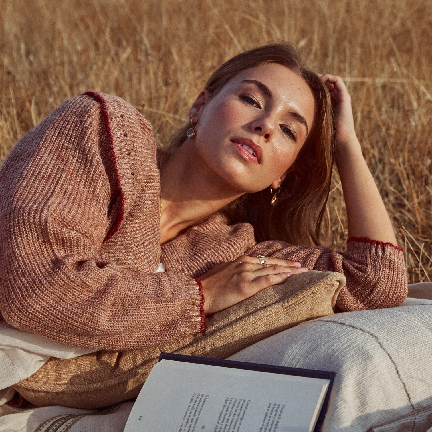Modelo leyendo tumbada en el campo, con los pendients Ophelia.