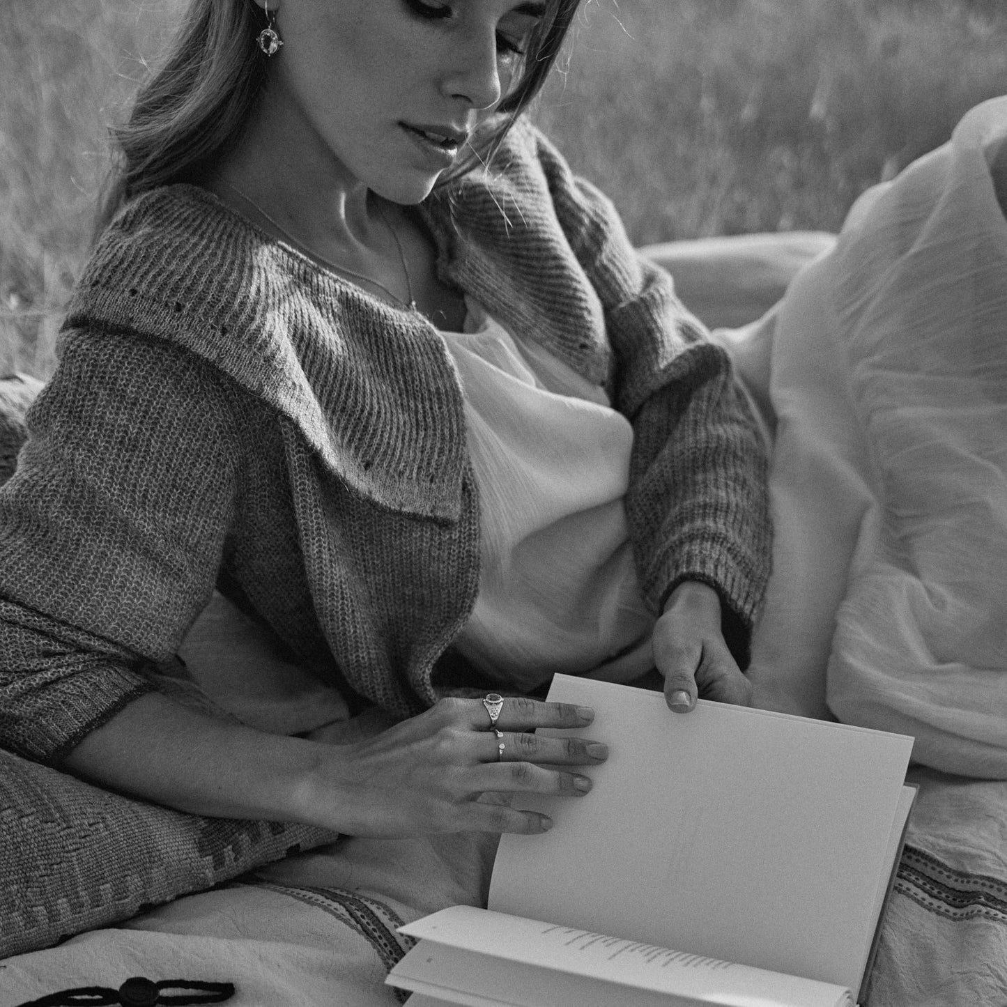 Mujer leyendo en el campo y mostrando el anillo Ophelia.
