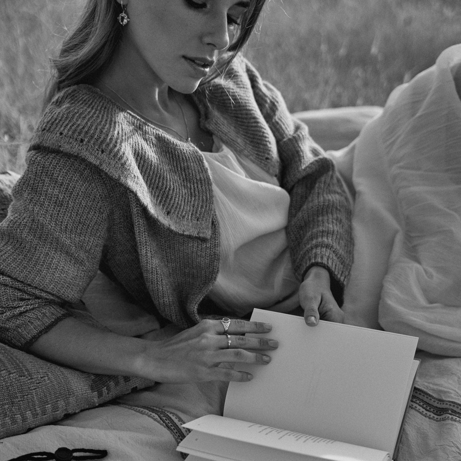 Mujer leyendo en el campo y mostrando el anillo Ophelia.