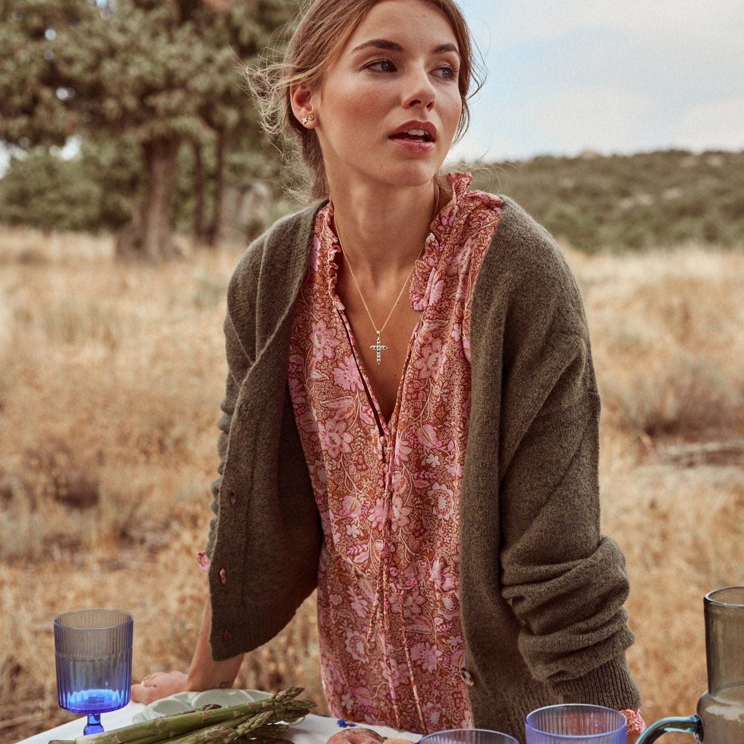 Mujer poniendo una mesa para una comida campestre. Lleva el collar Cruz Sofía.