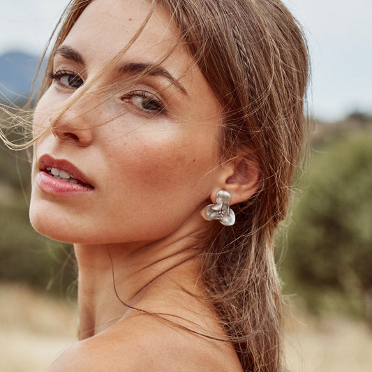 Perfil de una mujer con los pendientes Floralis tamaño grande y acabado mate.