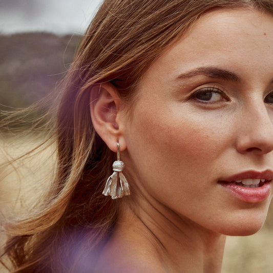 Foto de semi-perfil de modelo llevando los Pendientes Autumn Flower. Elaborados a mano y trabajados, pétalo a pétalo, para conseguir una textura natural y con movimiento.