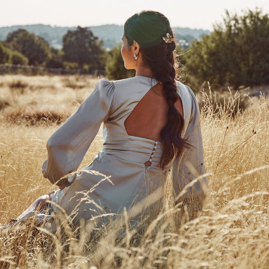 Modelo sentada en un campo de espigas con una trenza de raíz y la Peineta Fôret, con forma de ramillete de hojas silvestres. Hecha artesanalmente con plata de ley.