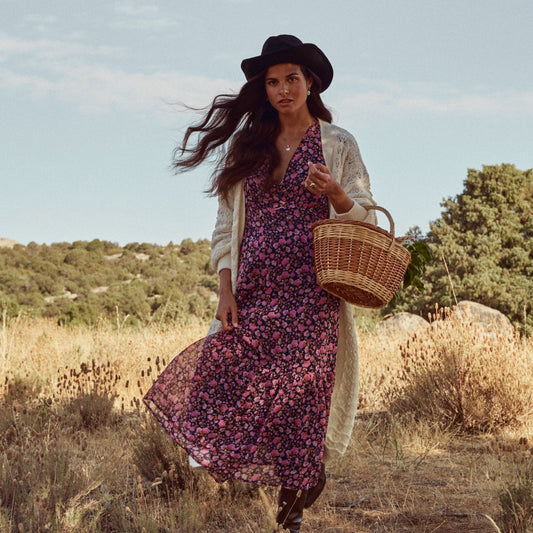 Mujer que va paseando por el campo con una cesta y muestra el colgante Delphine.