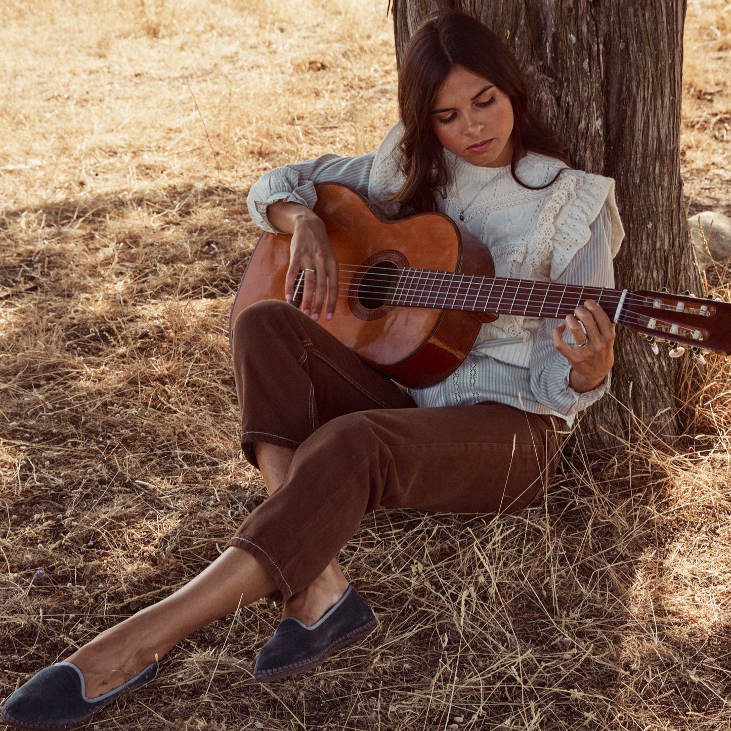 Mujer tocando la guitarra en el campo con el colgante Yvette.
