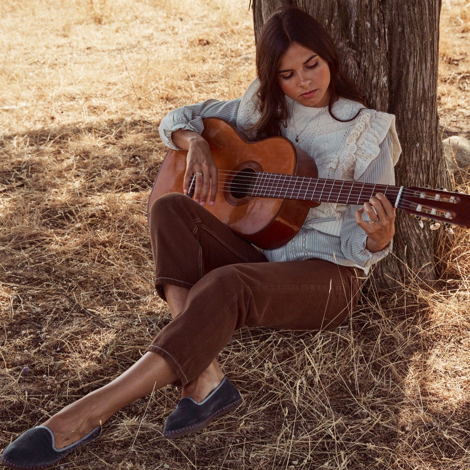 Mujer tocando la guitarra en el campo con el colgante Yvette.