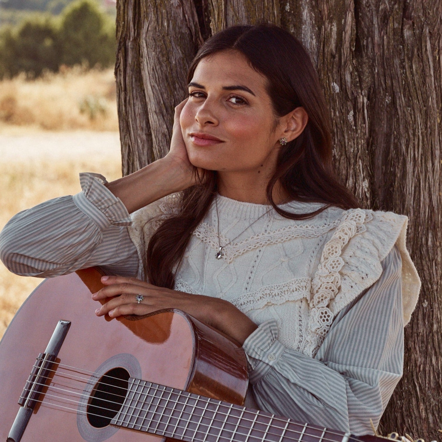 Modelo posando apoyada en un árbol con una guitarra. Lleva los Pendientes Yvette, a juego con collar y anillo. Los pendientes están hecho con plata de ley y llevan engastadas una amatista y 8 granates verdes cada uno.