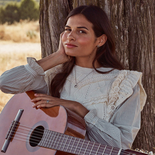 Mujer sonriendo con una guitarra y con el colgante Yvette.