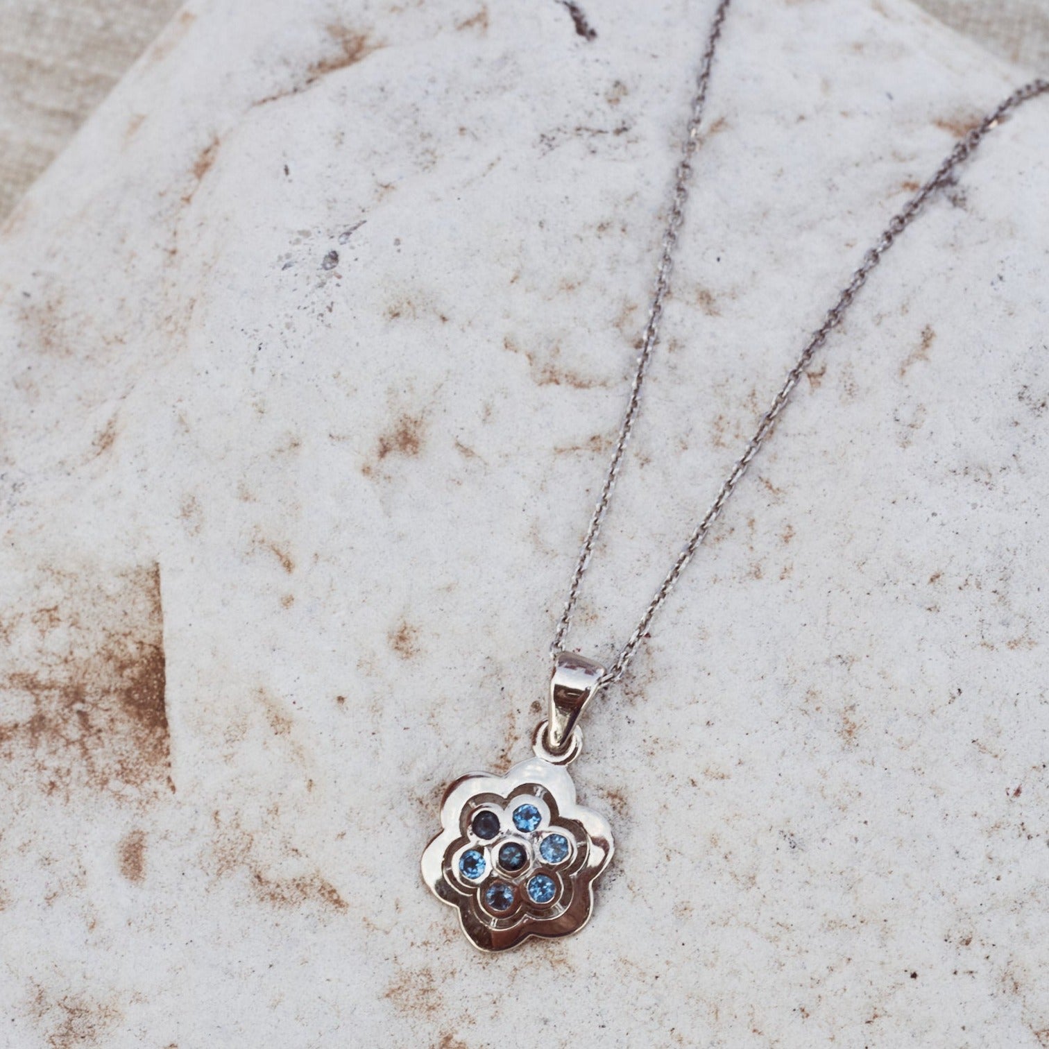 Detalle del colgante Delphine donde se aprecia su diseño con forma de flor y siete topacios London engastados.